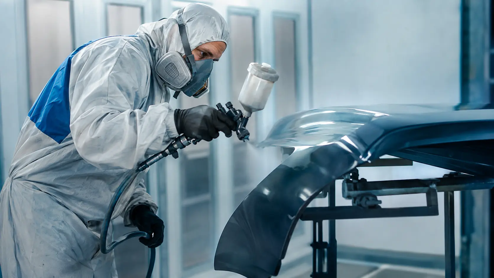 Profissional realizando pintura de uma peça automotiva em cabine moderna